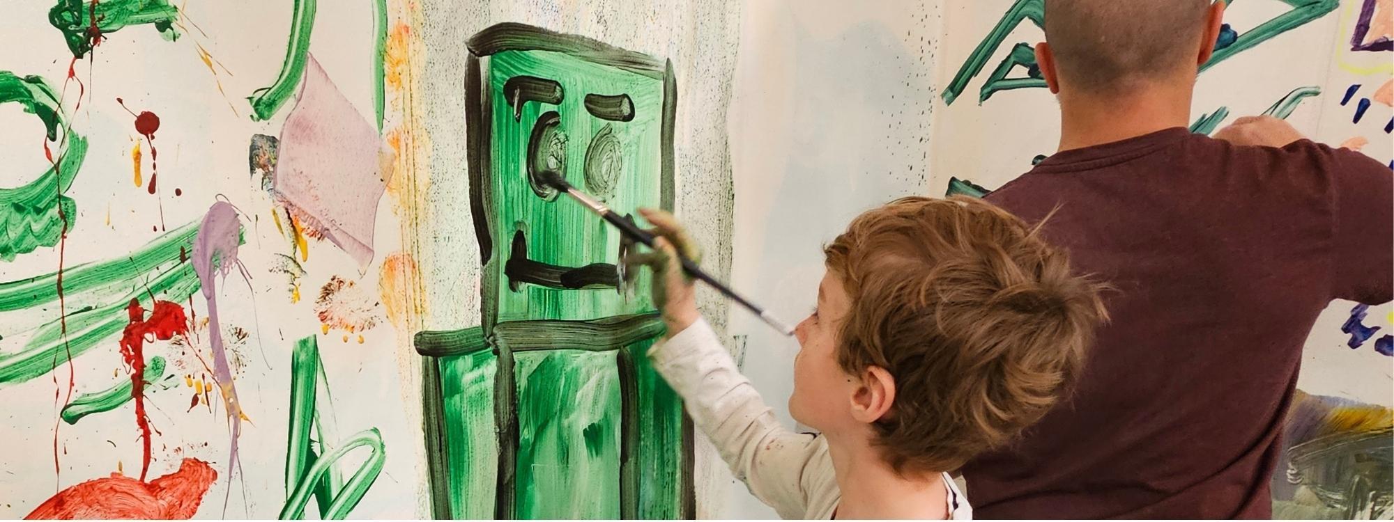 Young boy painting a green robot