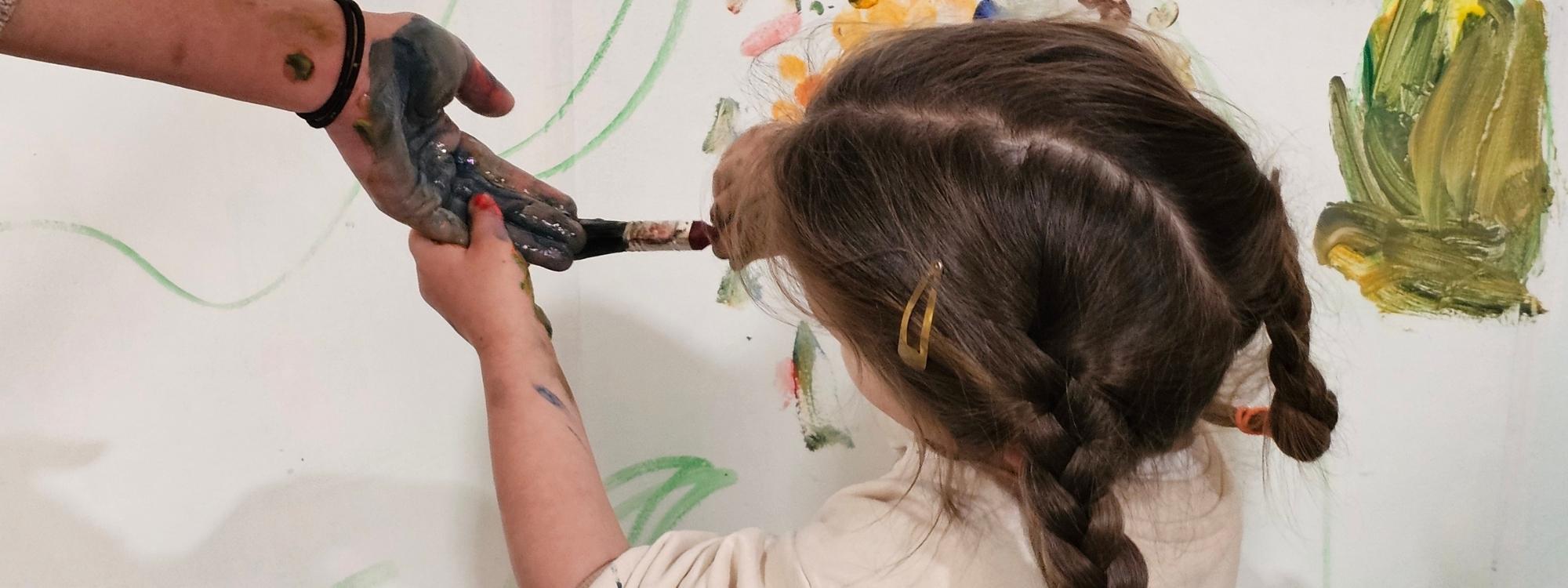Young girl painting her mum hand